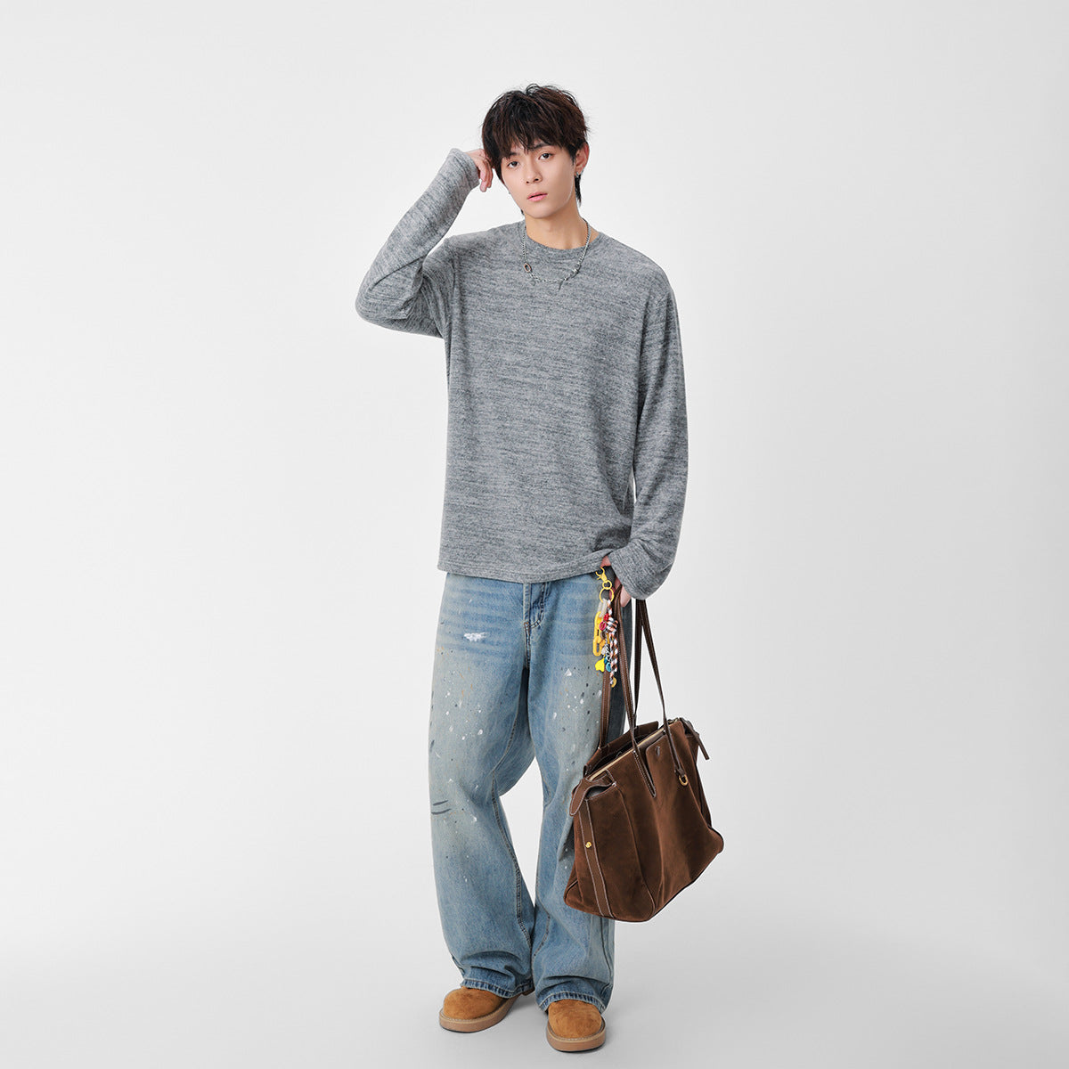 Full-length model wearing a marled gray crew-neck sweater and loose light-wash jeans.