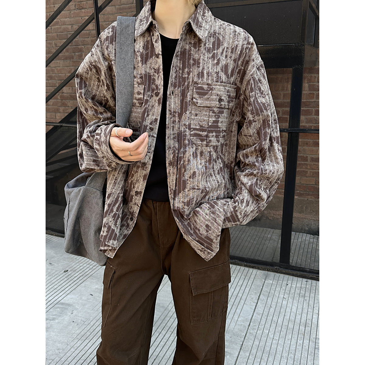 Close view of a model wearing a brown and beige abstract-stripe button-up shirt with two flap chest pockets.