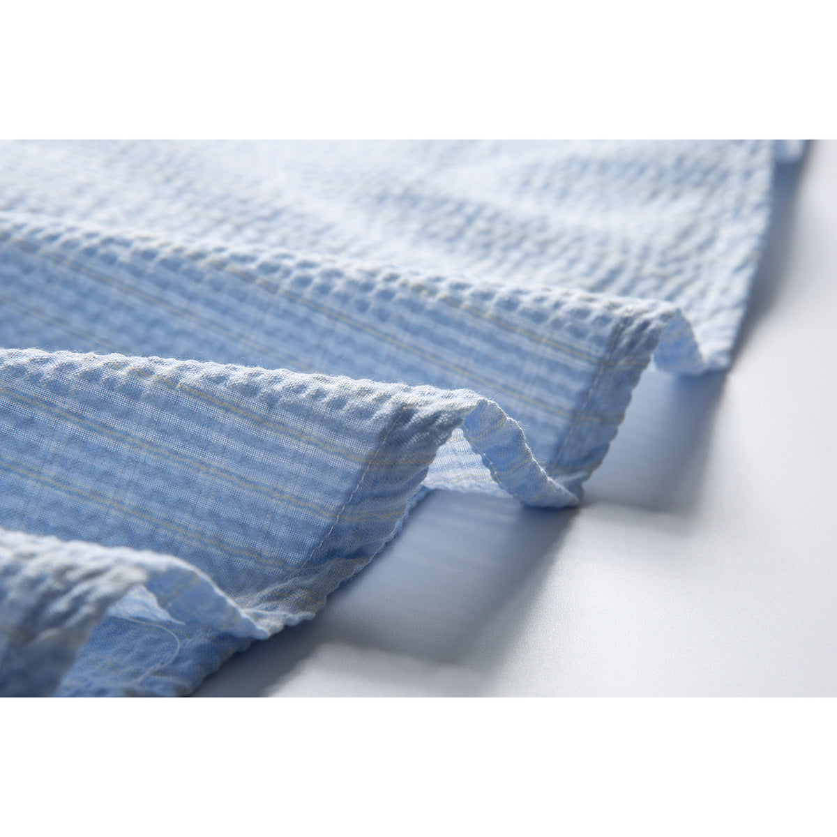 Close-up of the light blue shirt's textured fabric and curved stitched hem.
