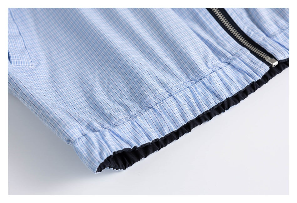 Close-up of the gathered black-trimmed hem and zipper on a light blue plaid garment.