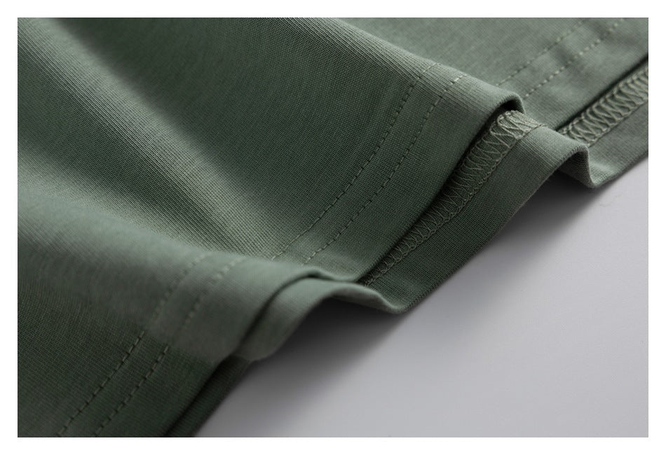 Close-up of a folded sage-green garment hem with seam stitching and overlocked edges.