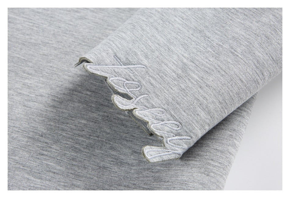Close-up of embroidered script at the cuff of a gray heather sweatshirt.