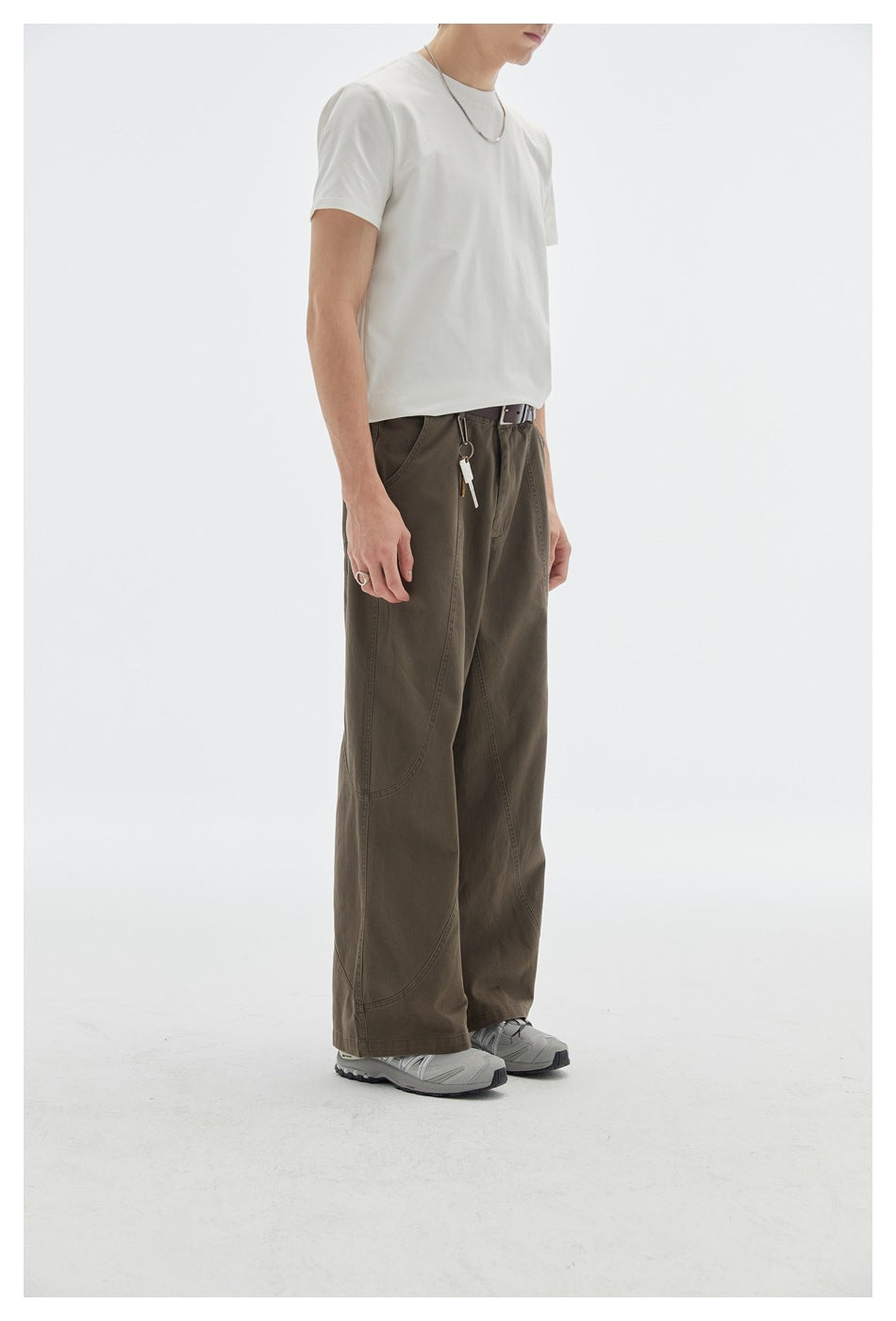 Three-quarter front view of a model wearing dark brown wide-leg pants with curved seams and a white T-shirt.