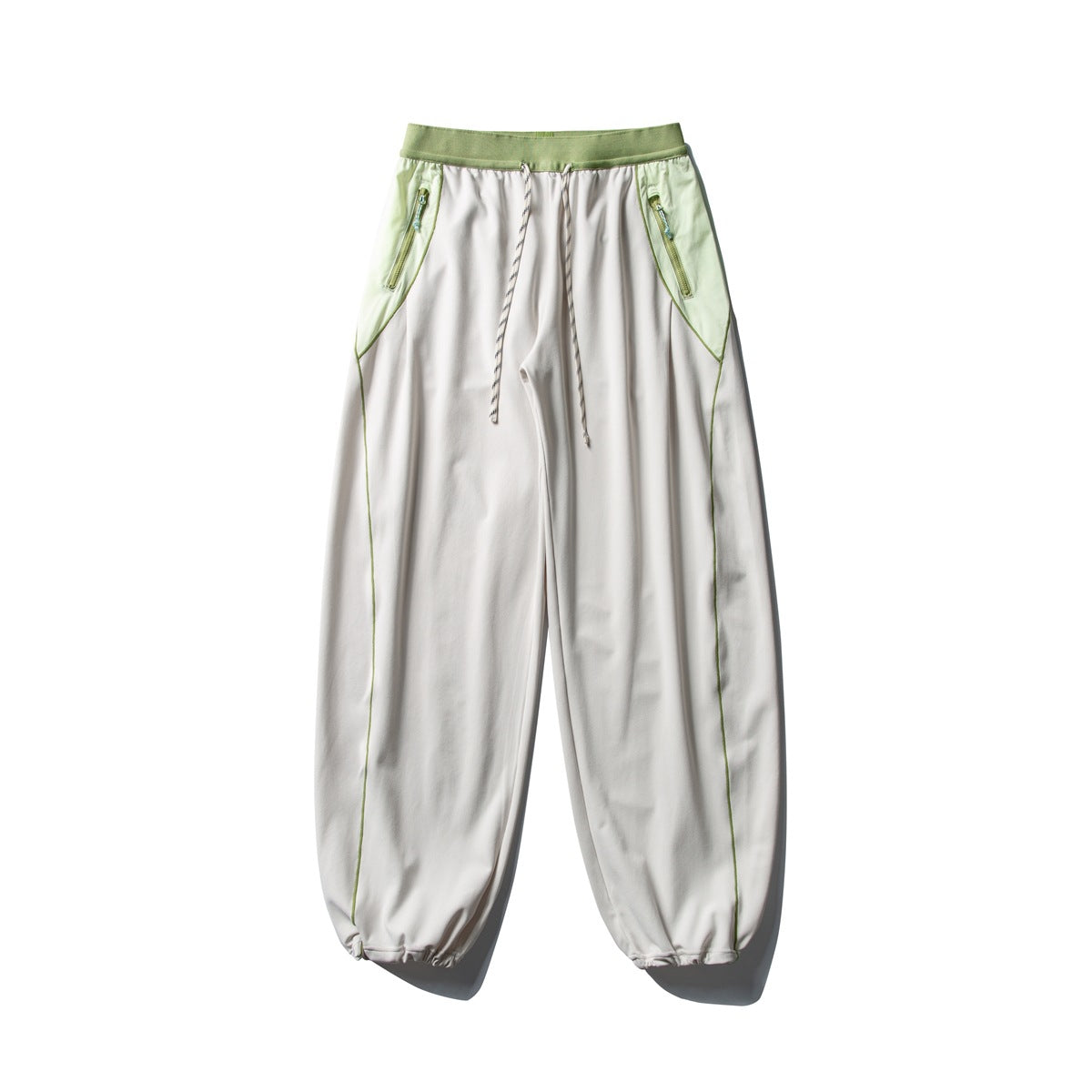 Front view of white wide-leg pants with a light green waistband and zip-pocket panels, drawstring, and gathered cuffs.
