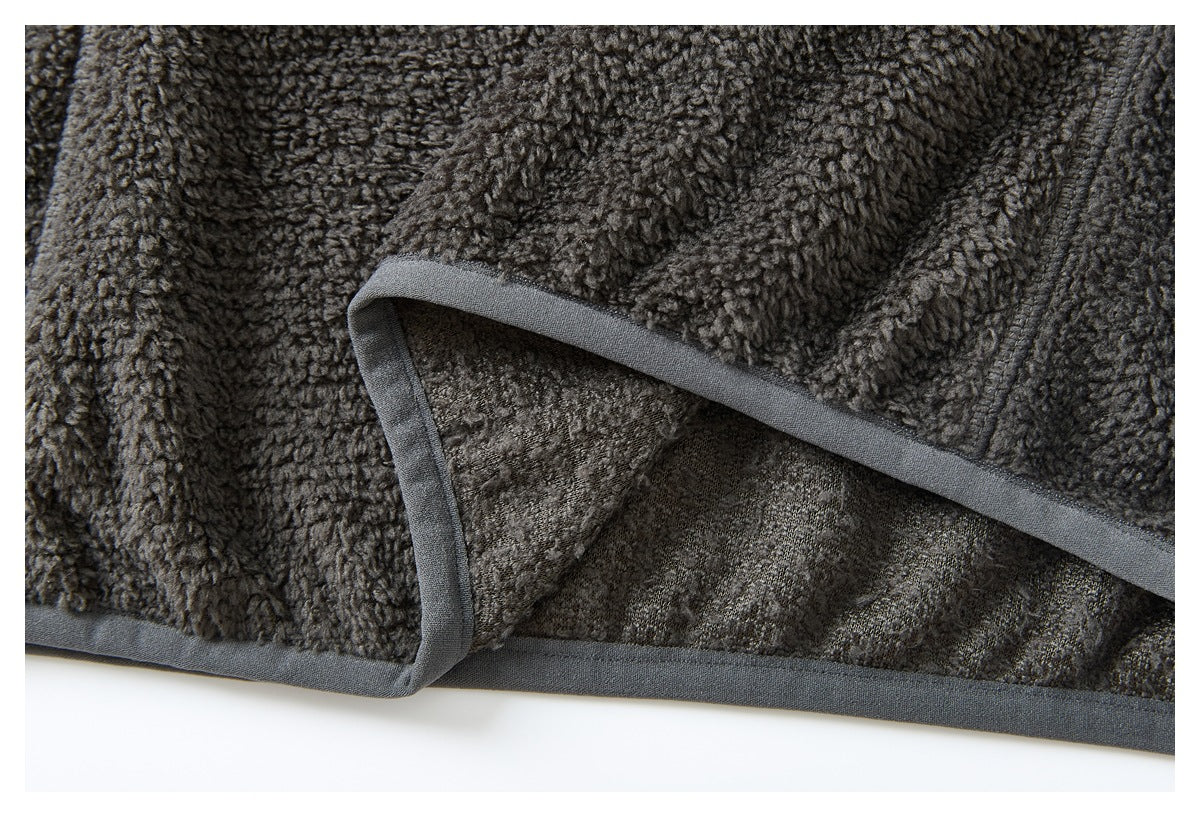 Close-up of the charcoal fleece jacket's bound hem, folded back to show the inner fabric.