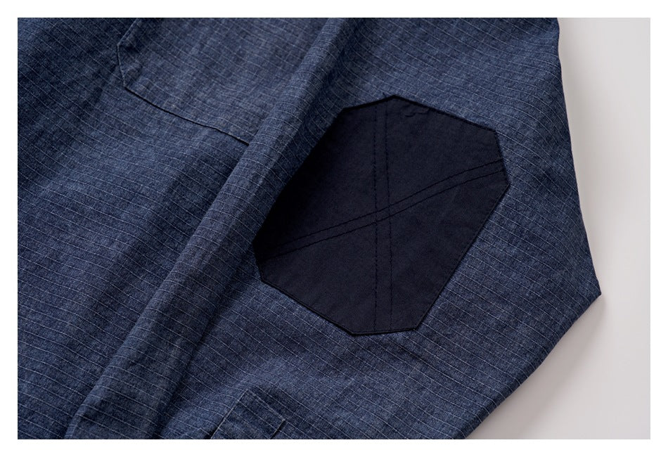 Close-up of a dark octagonal patch stitched onto the sleeve of a blue grid-patterned shirt.