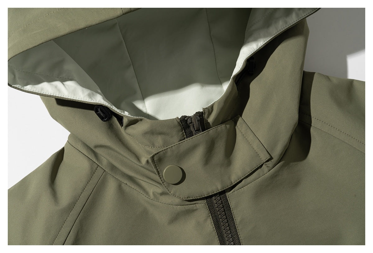 Close-up of an olive jacket's hood, high collar, snap tab and dark front zipper.