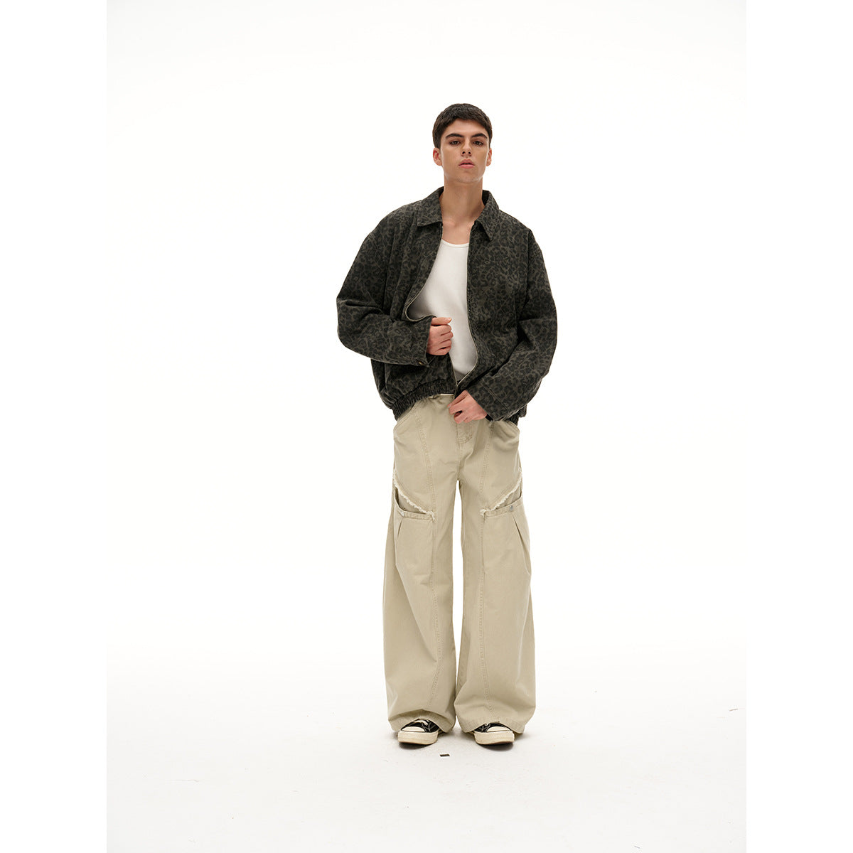 Model wearing a dark leopard-print zip jacket, white top, and loose beige cargo trousers, shown full length.
