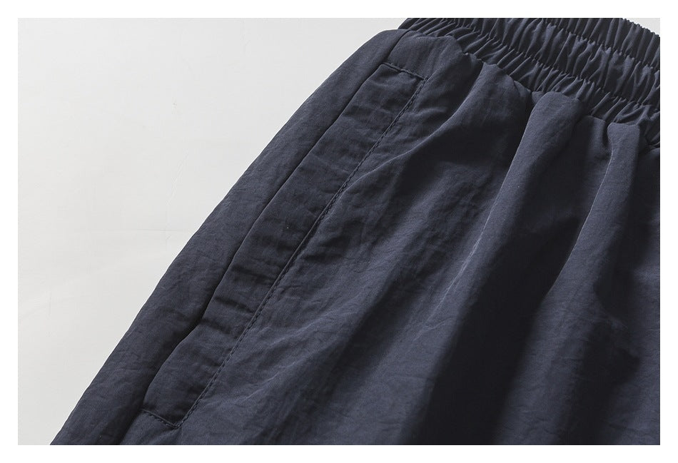 Close-up of a side pocket and gathered elastic waistband on the dark navy pants.