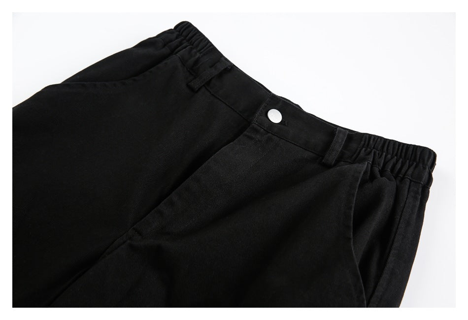 Close-up of black shorts showing the waistband, silver button, belt loops, and front pocket.