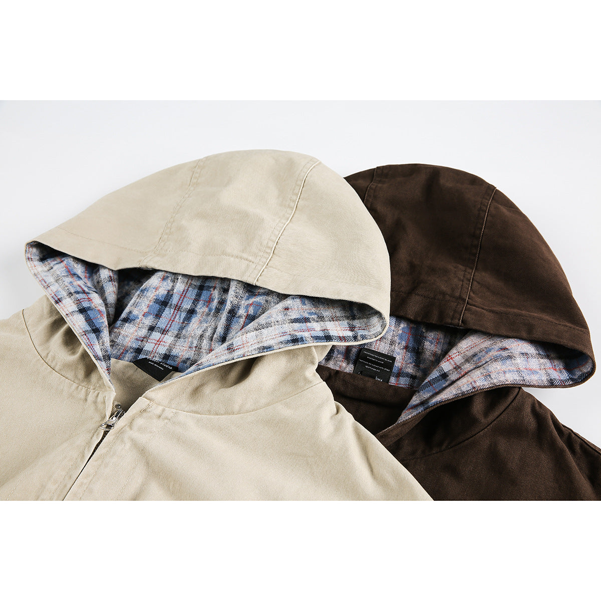 Close-up of beige and dark brown hooded jackets showing blue, gray, and red plaid hood linings.