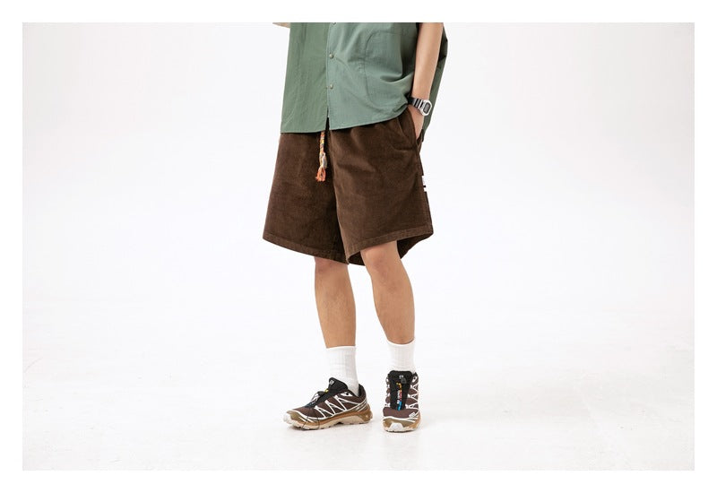 Model wearing brown knee-length shorts with a colorful braided tassel drawstring and side pockets.