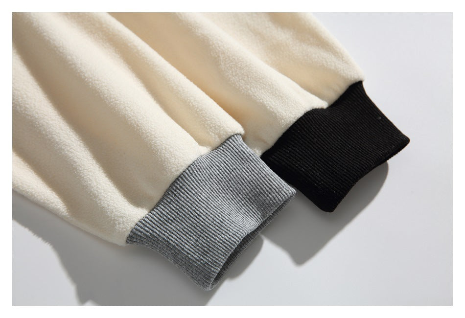 Close-up of cream sleeves with one gray ribbed cuff and one black ribbed cuff.