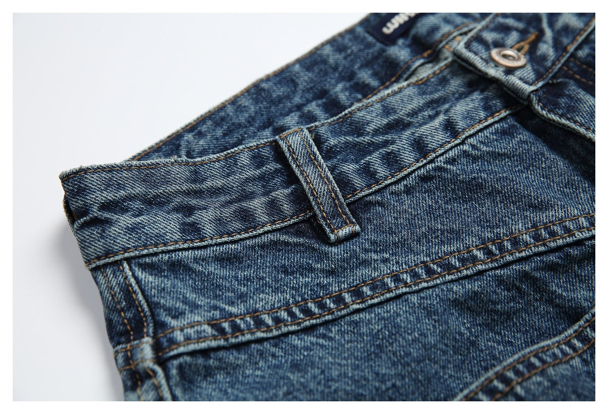Close-up of blue jeans at the waist, showing a belt loop, metal button, and waistband stitching.