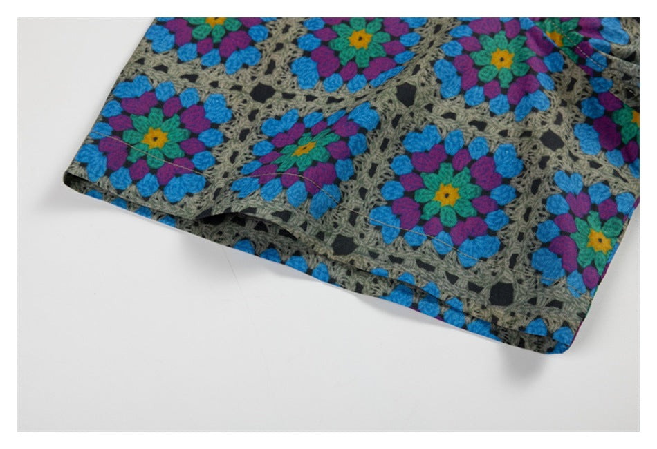 Close-up of a stitched shirt edge in a gray-based, multicolor floral geometric print.