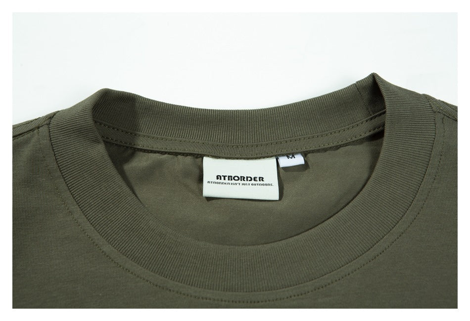Close-up of the olive-green T-shirt's ribbed crew neck and sewn-in brand and size labels.