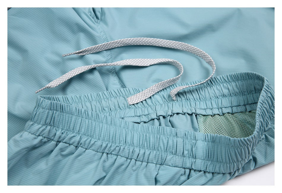 Close-up of pale aqua shorts waistband with a white drawstring and mesh-lined pocket.