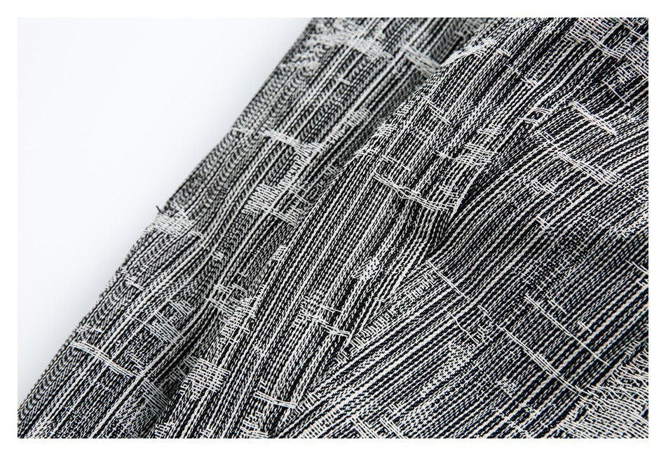 Close-up of black-and-white fabric with a dense, irregular woven pattern.