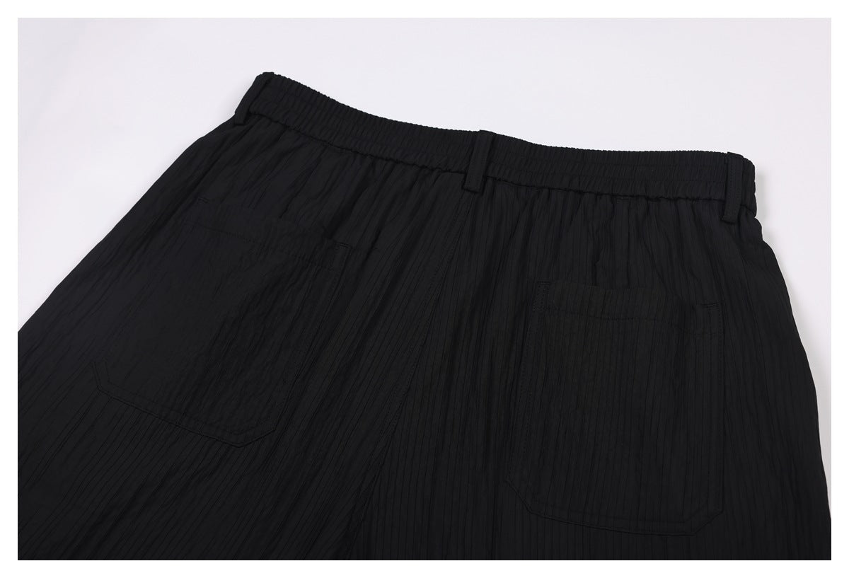Close-up of black trousers showing an elasticated waistband, belt loops, and two back pockets.
