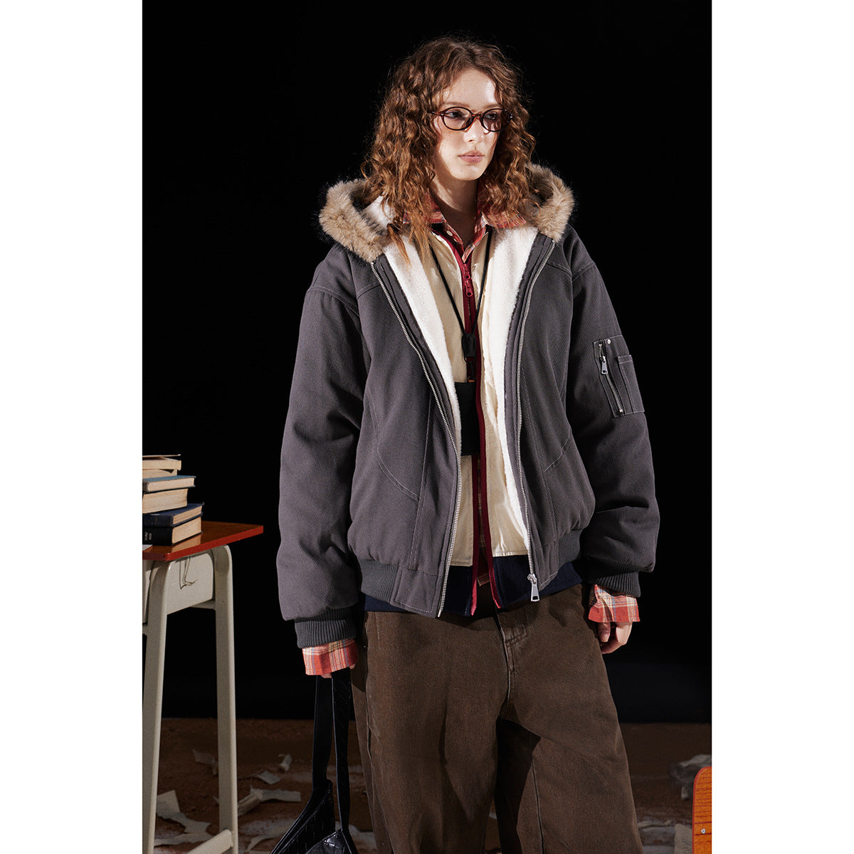 Model wearing a charcoal zip-front hooded jacket with cream lining, a faux-fur-trimmed hood and a zip sleeve pocket.