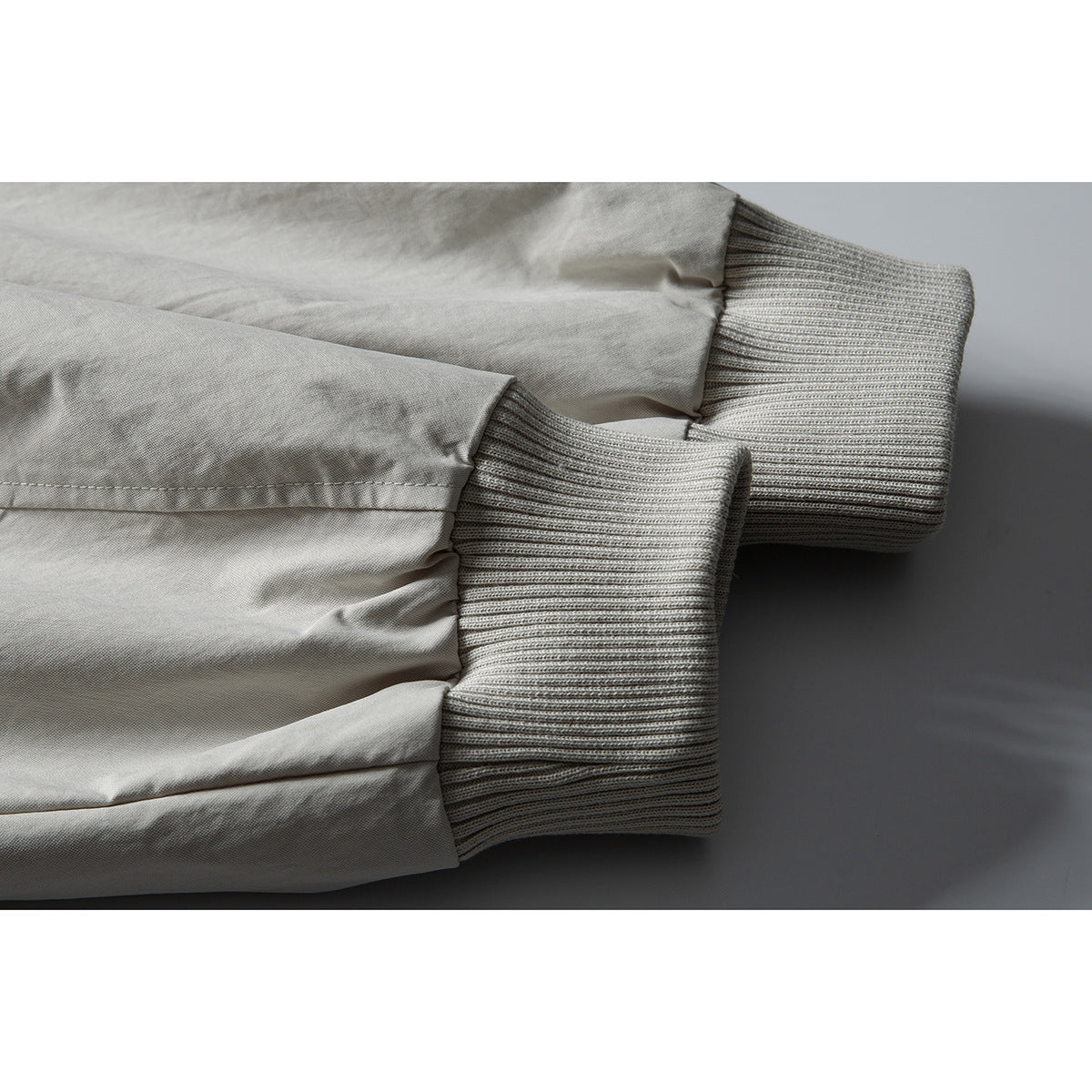 Close-up of two light gray jacket sleeves with wide rib-knit cuffs.