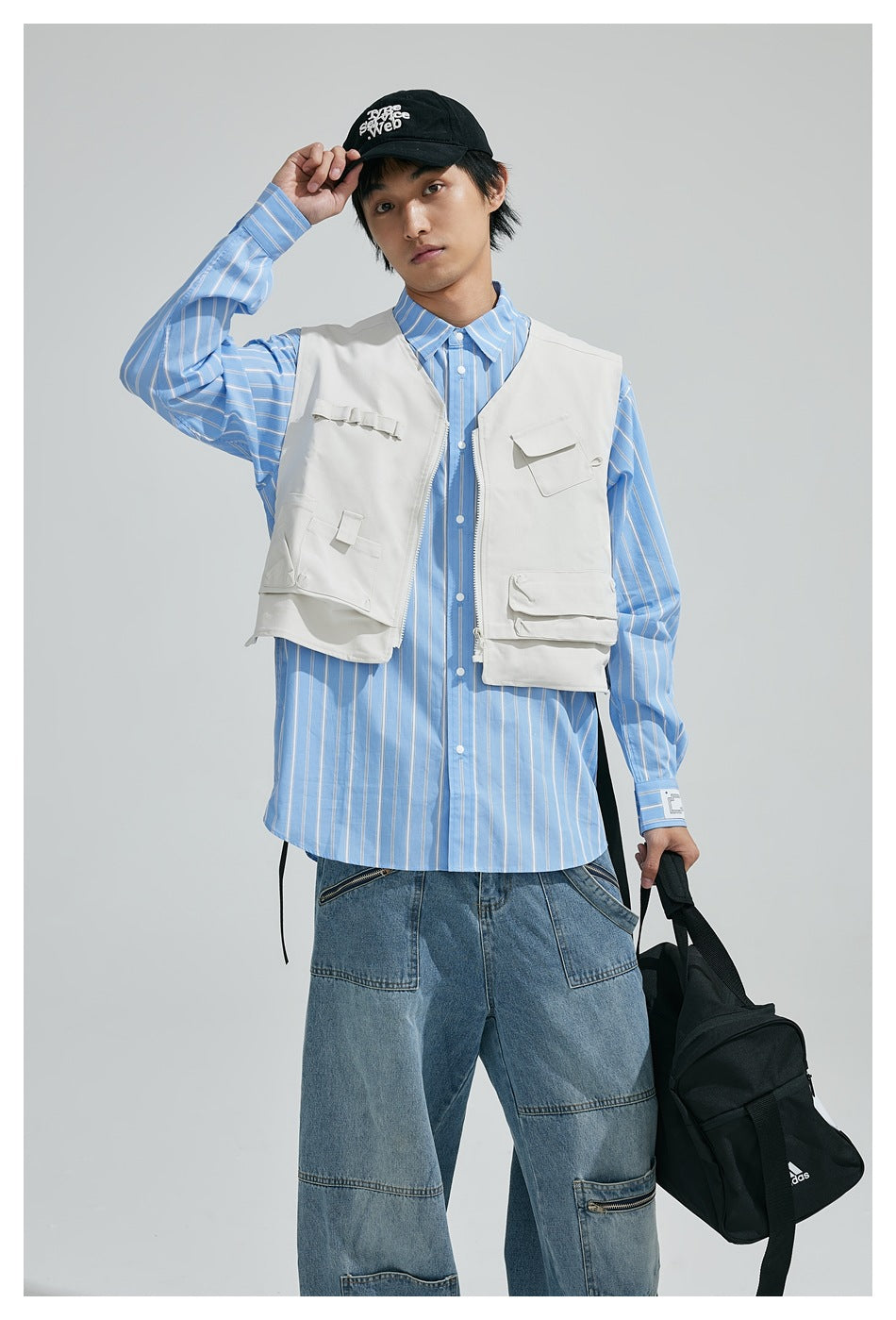 Front view of a model in a white multi-pocket utility vest over a blue striped shirt.