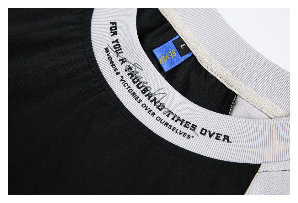 Close-up of the black shirt neckline with a light gray ribbed collar and printed lettering.