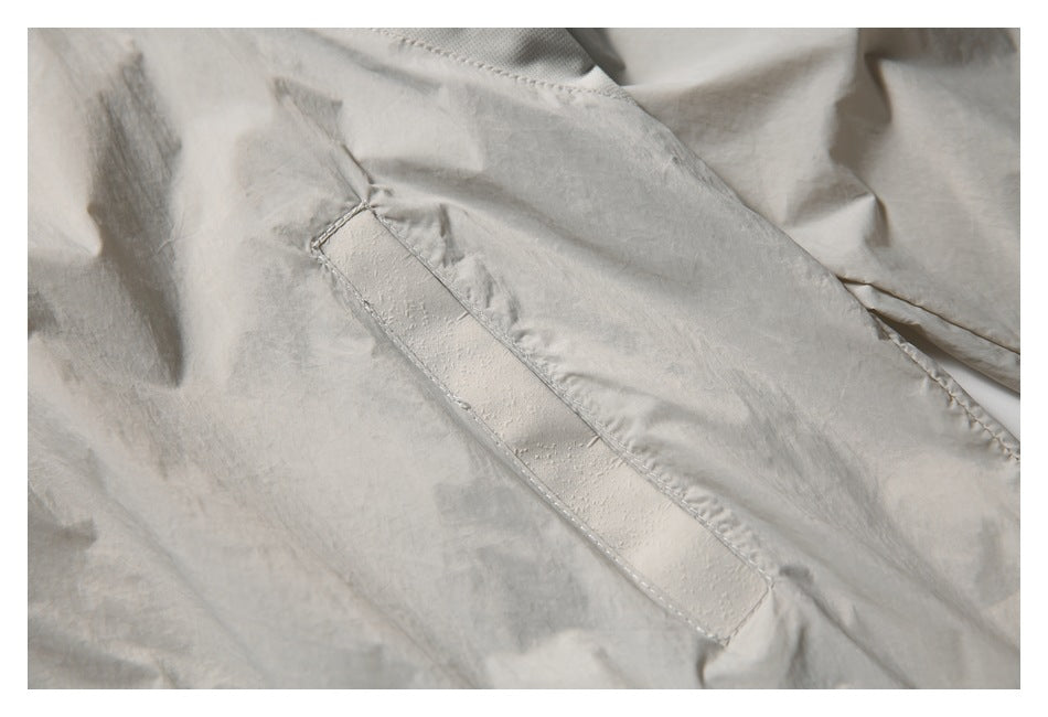 Close-up of a stitched rectangular tab on the light beige jacket.