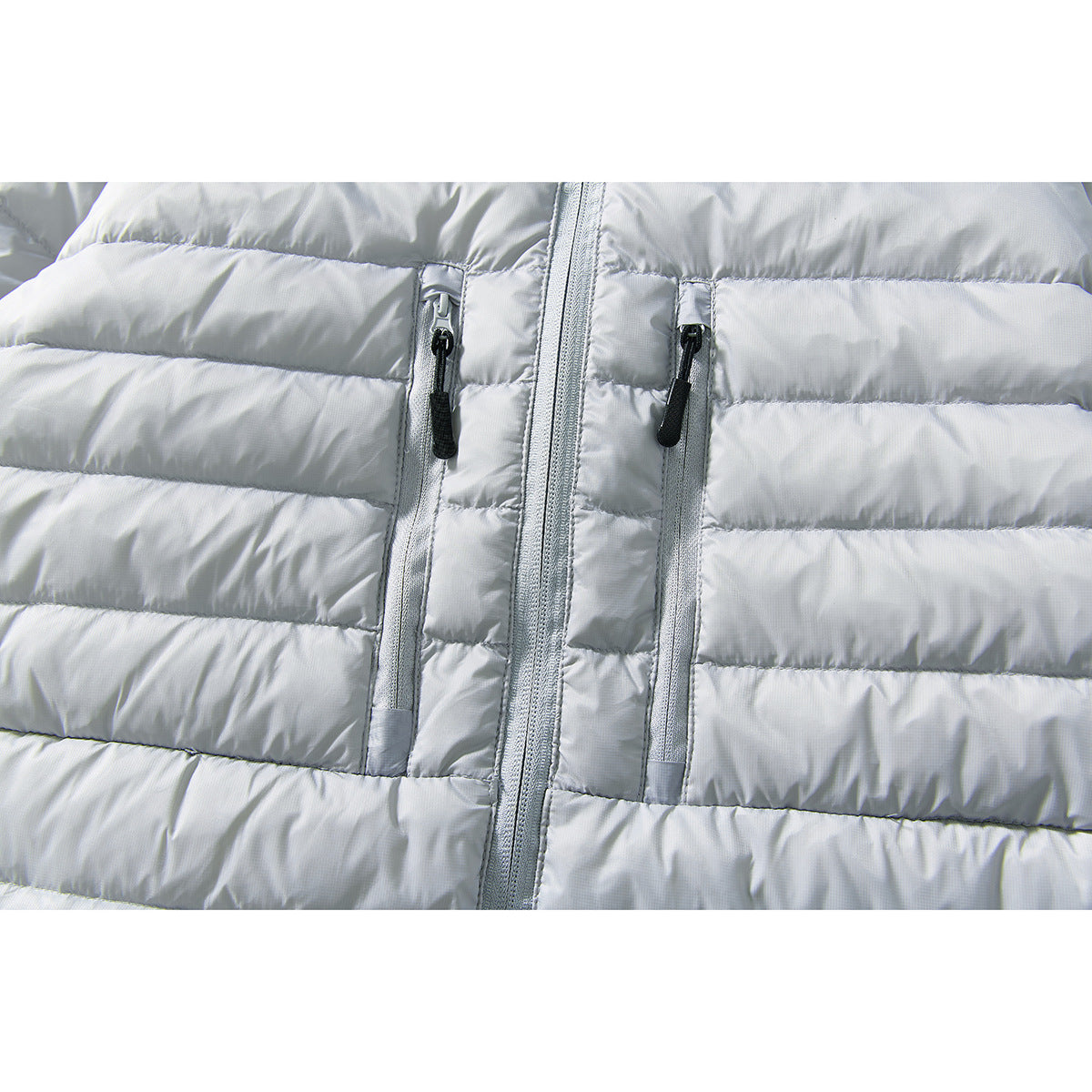 Close-up of a light gray quilted jacket with a central zipper and two vertical zip pockets.