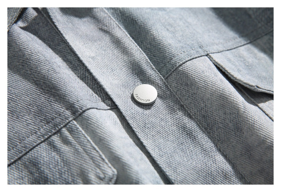 Close-up of the jacket's washed fabric, stitched seams, flap pocket edge, and snap button.