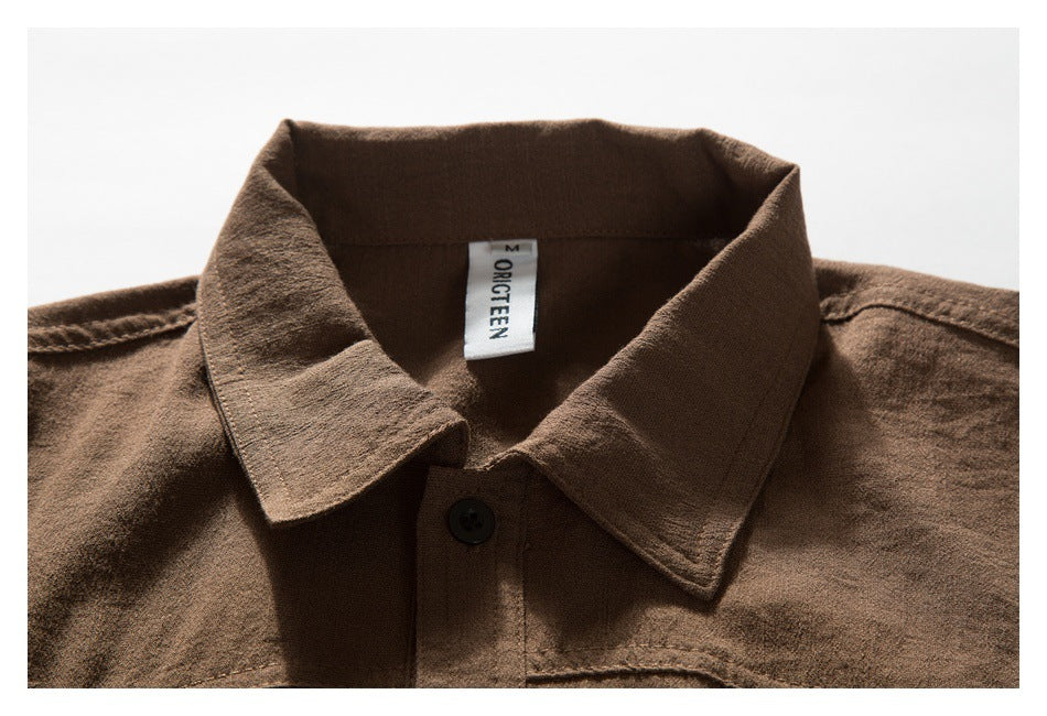 Brown shirt collar and upper front shown close up, with a black button and sewn neck label.