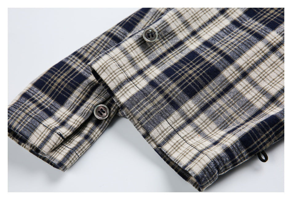 Close-up of navy, cream, and tan plaid garment edges with two dark buttons and a small loop.