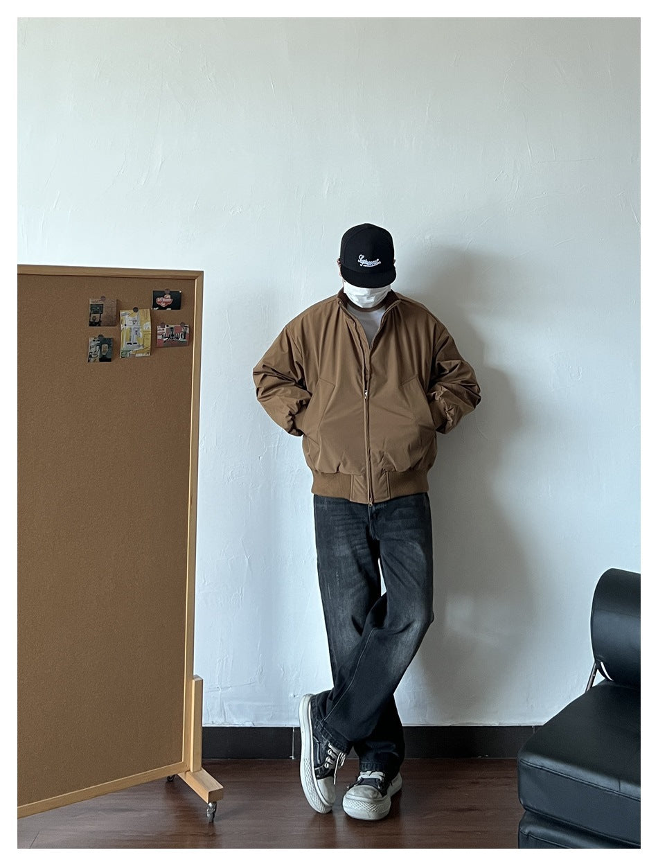 Person wearing the brown zip-front jacket with hands in the pockets, paired with dark jeans and sneakers.