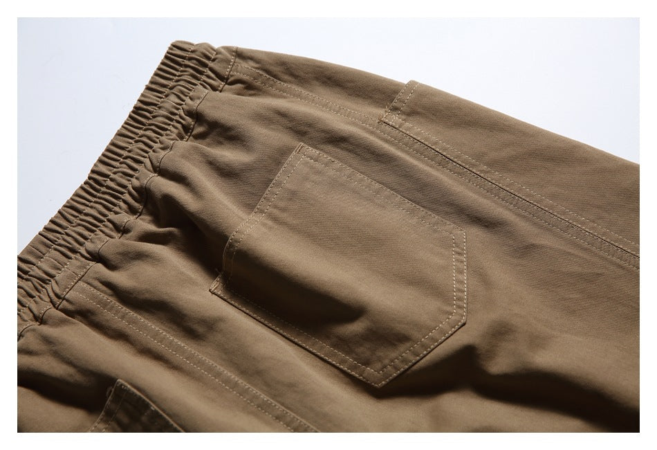 Close-up of a stitched patch pocket on the back of brown pants, with part of the elastic waistband visible.