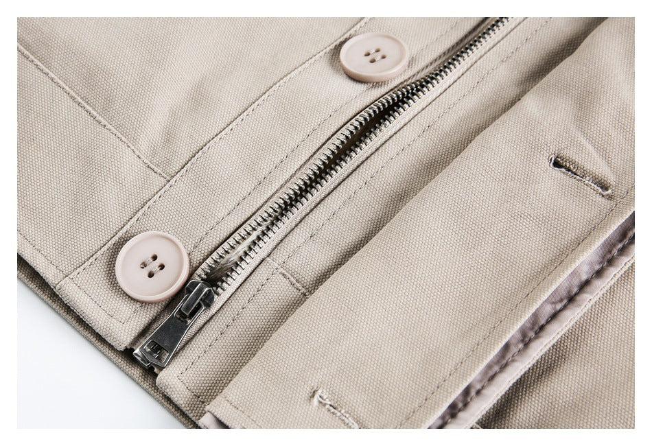 Close-up of a beige garment's metal zipper, pale buttons, and stitched buttonholes.