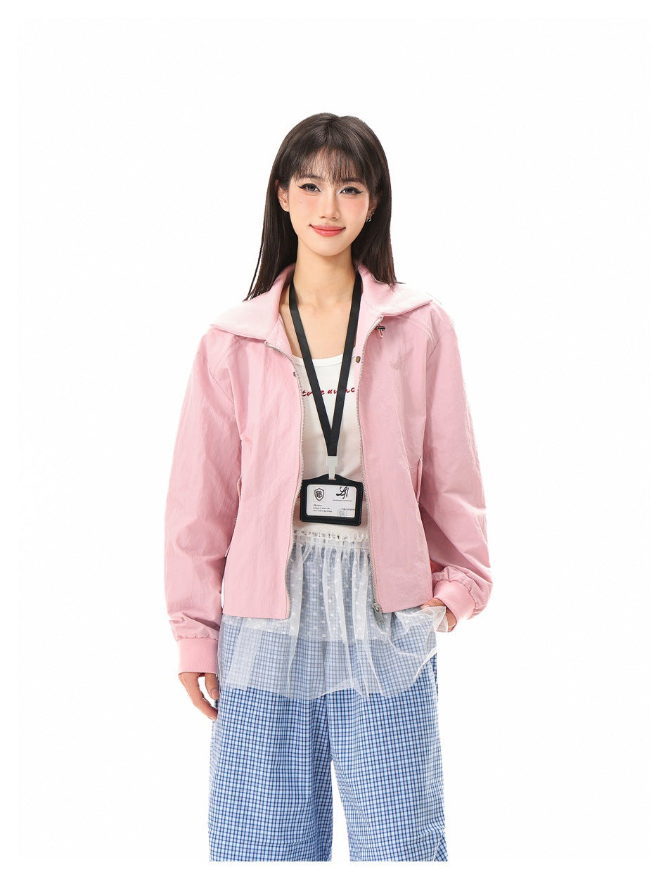 Close-up of model in pink zip jacket with collar, ID lanyard, sheer layered skirt and blue plaid pants