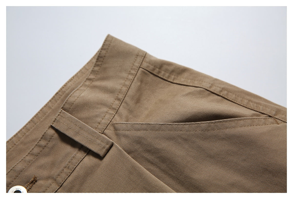 Close-up of the tan trousers' waistband and belt loop, with part of a metal button visible.
