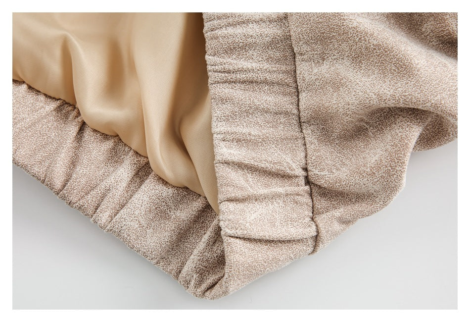 Close-up of a gathered elastic waistband and smooth beige lining on a mottled garment.