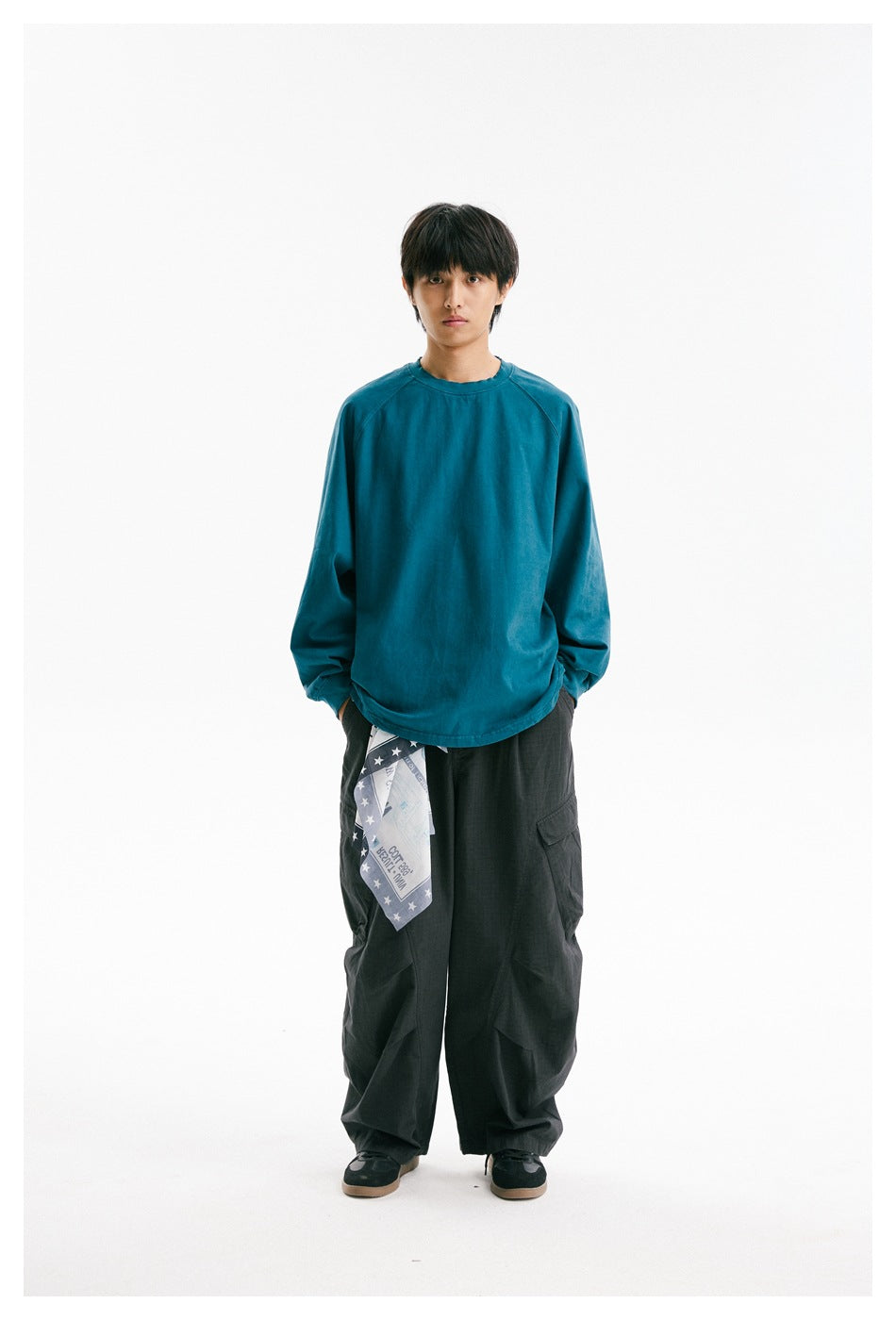 Full-length model wearing a teal raglan long-sleeve shirt and dark wide-leg cargo trousers.