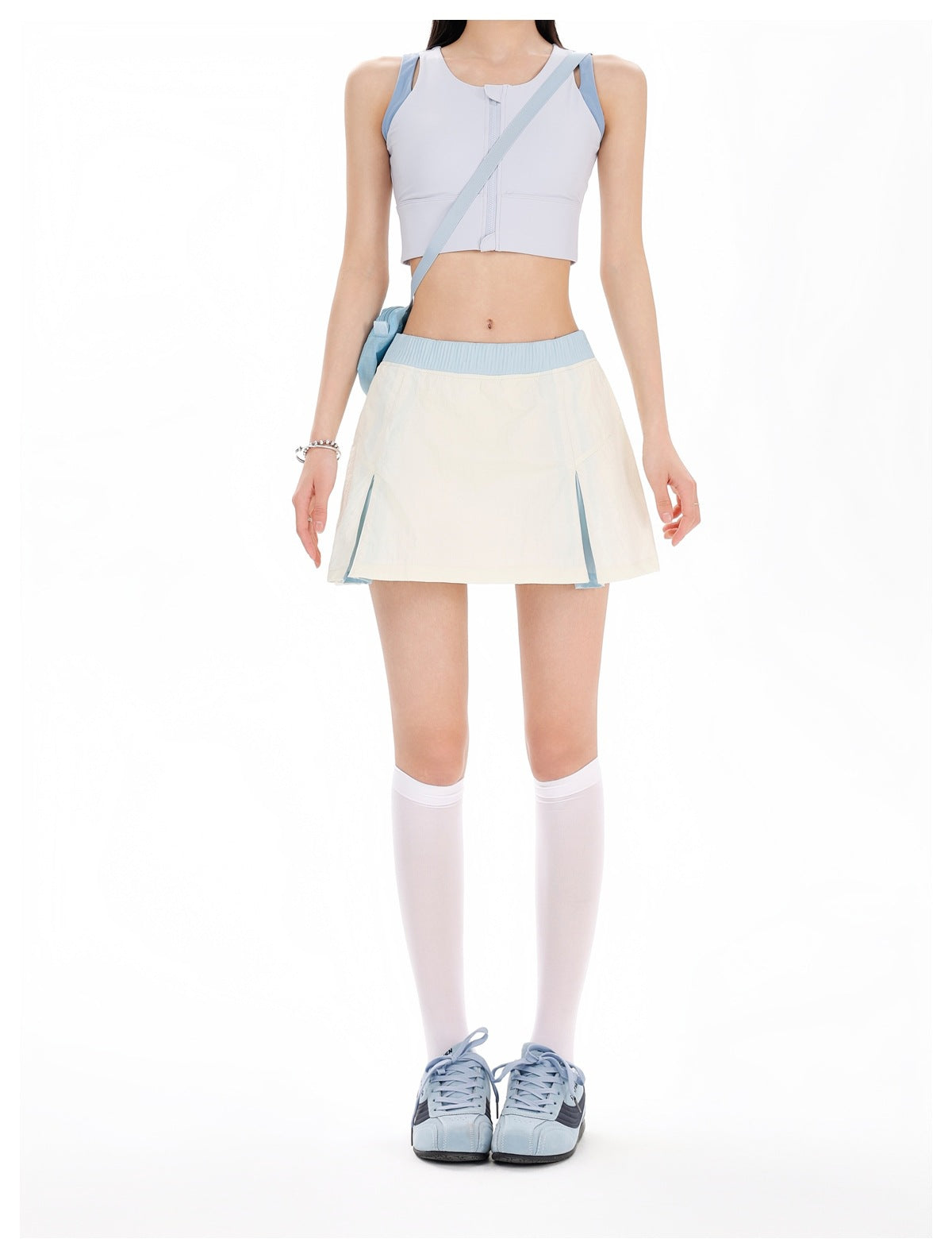 Model wearing an off-white mini skirt with light blue waistband and front slits, with white knee socks and blue sneakers