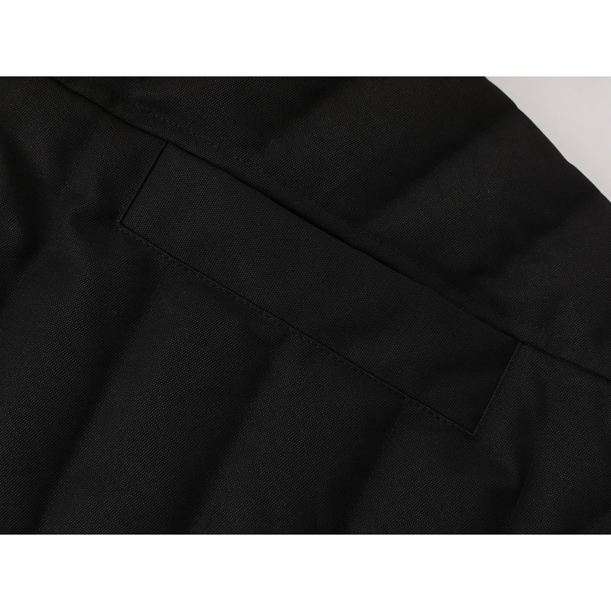 Close-up of black jacket fabric and a stitched rectangular seam detail.