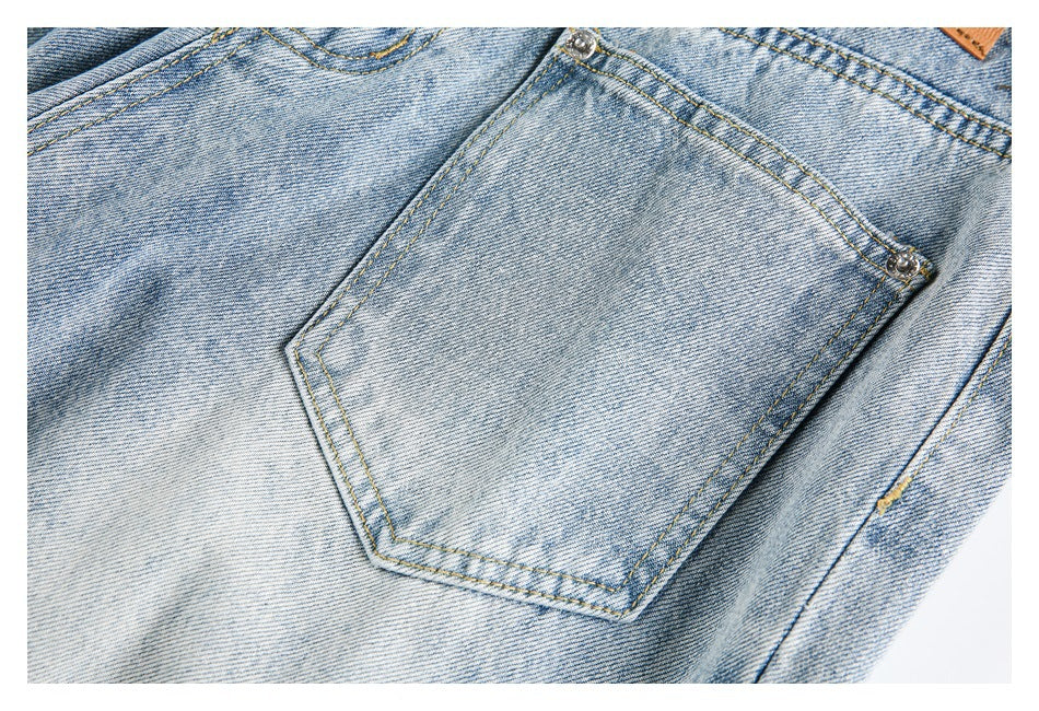 Close-up of a light blue denim back pocket with contrast stitching and metal rivets.