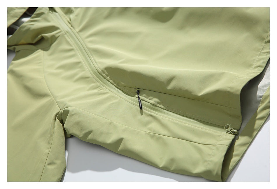 Close-up of a pale olive jacket with a diagonal seam and zippered pocket.