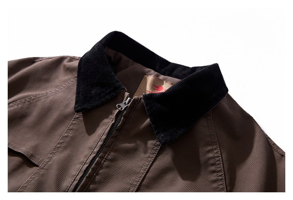 Close-up of a brown jacket's black corduroy collar, zipper, and stitched front panels.