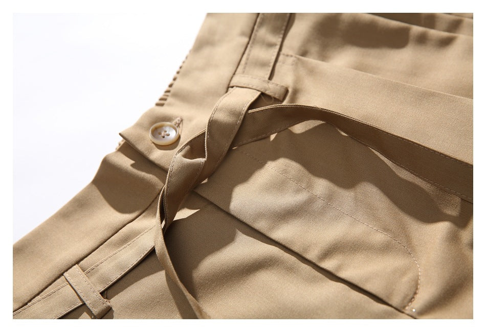 Close-up of the tan trousers' buttoned waistband, belt loop, and matching tie belt.