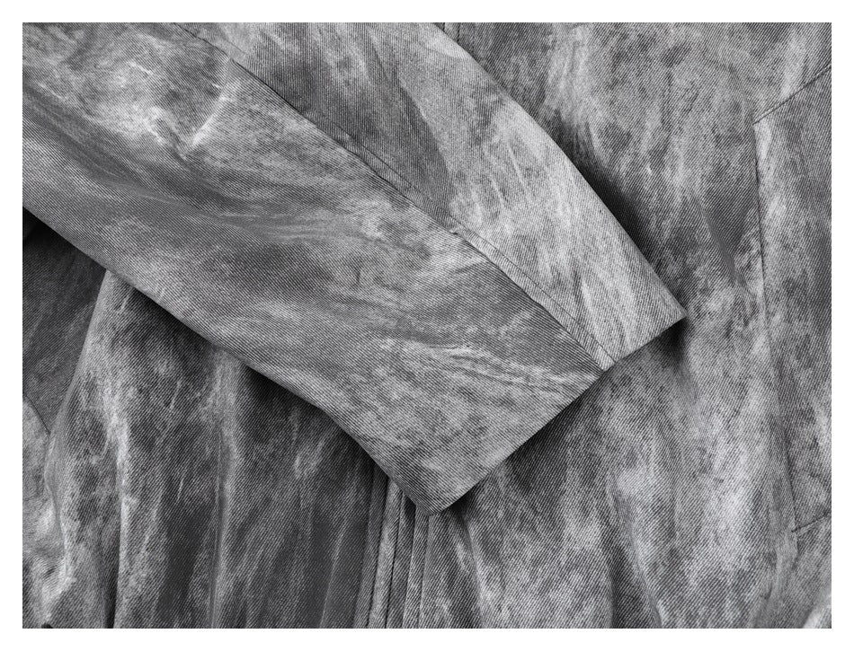 Close-up of gray acid-wash garment fabric, showing overlapping panels and a stitched seam.