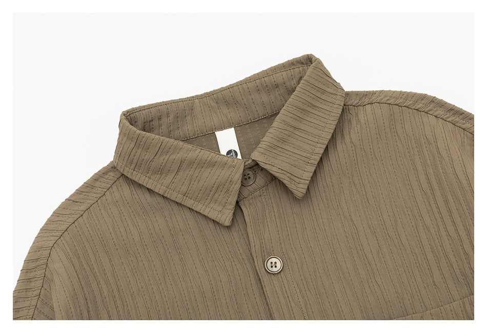 Close-up of a taupe shirt collar, top button, and vertically textured striped fabric.