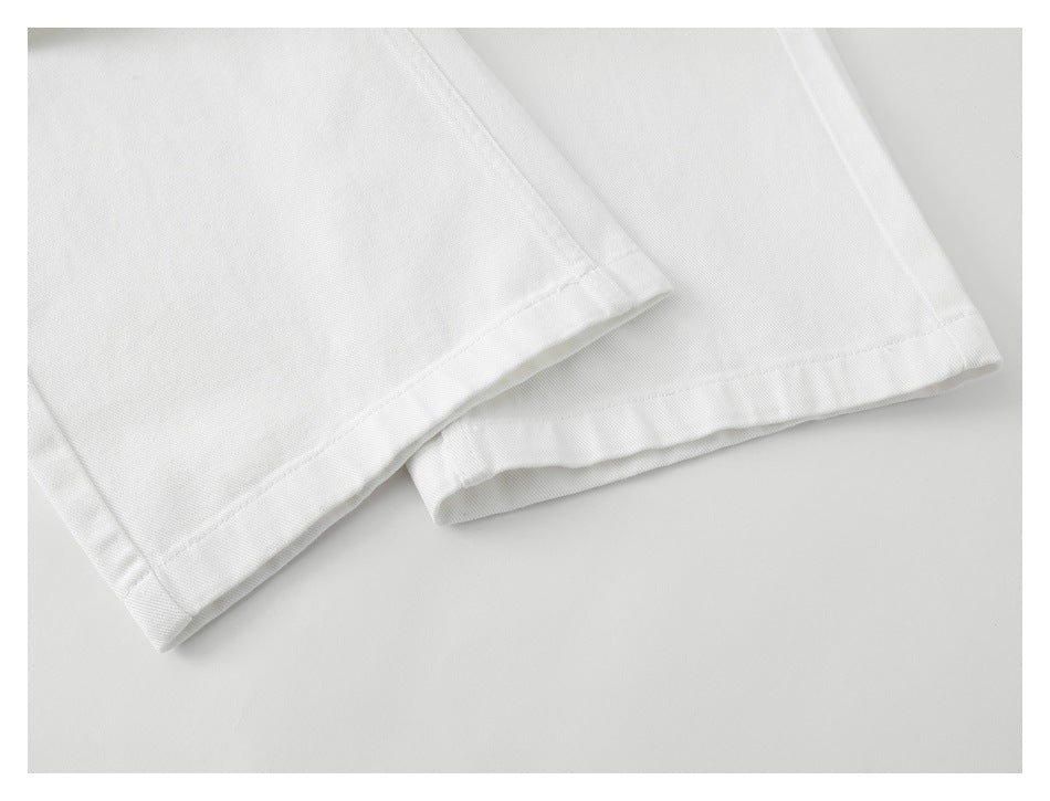 Close-up of the straight stitched hems on white trouser legs.
