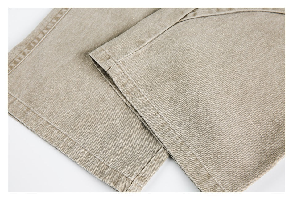 Close-up of overlapping beige trouser legs with stitched hems.