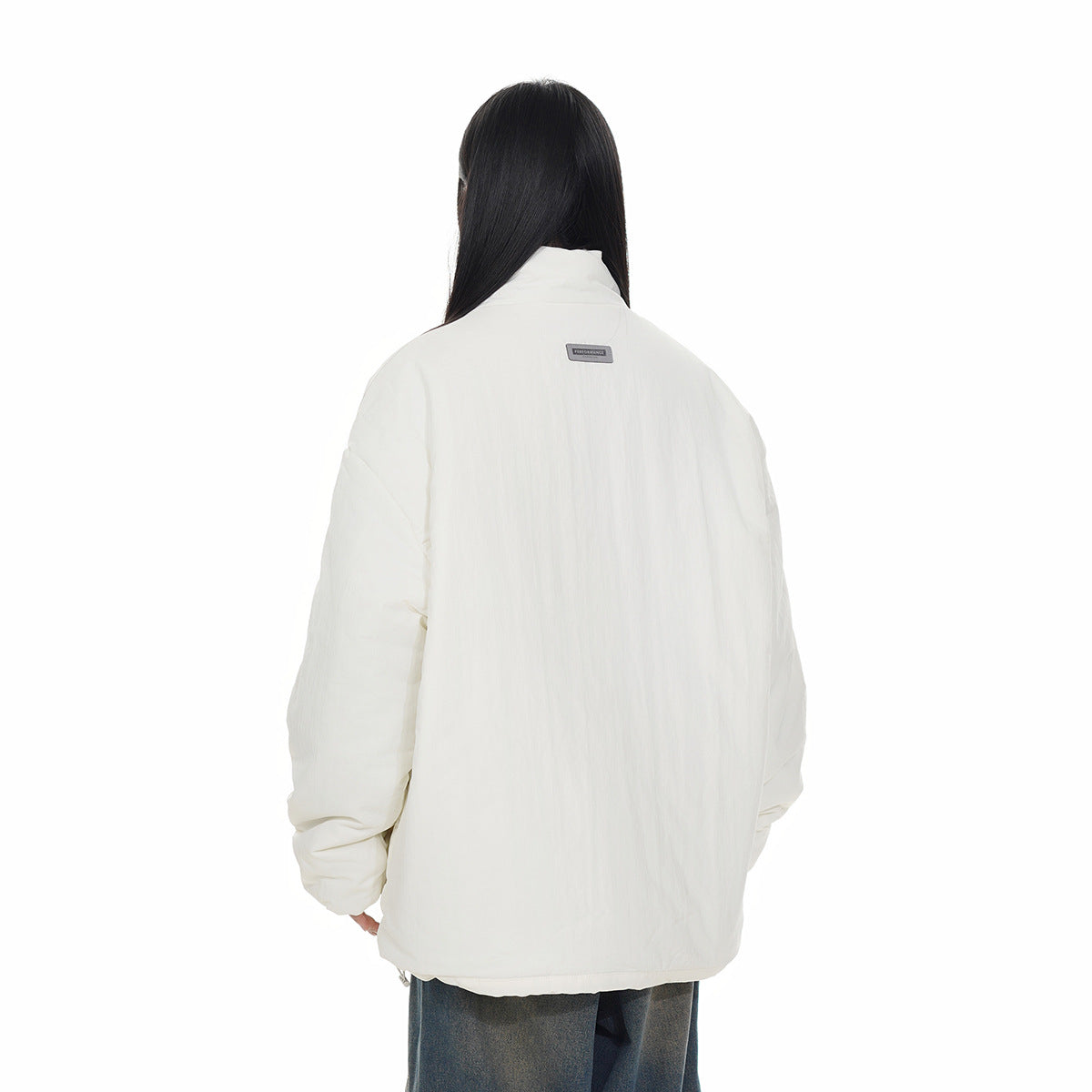 Rear view of a model wearing an oversized ivory padded jacket with a high collar and dropped shoulders.